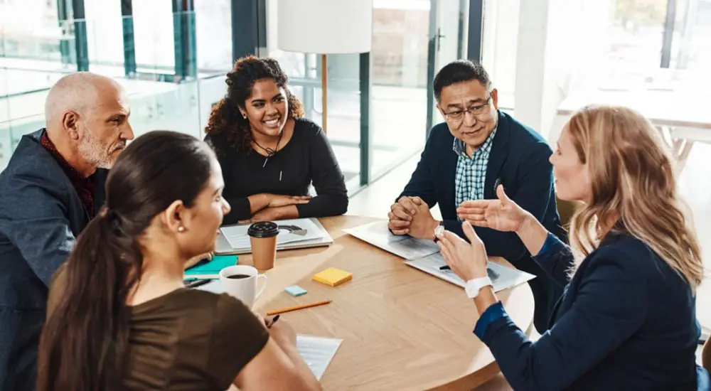 A diverse group of adults having a discussion around a table.