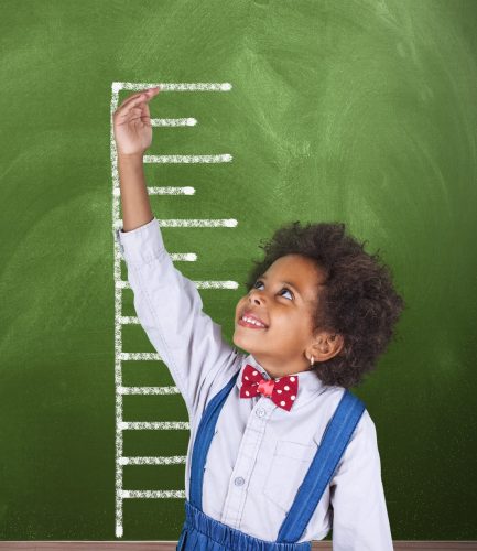 African schoolgirl is showing height on a blackboard scale