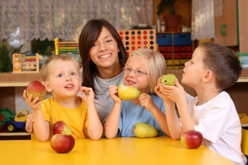 teacher and three preschoolers having break for fruits