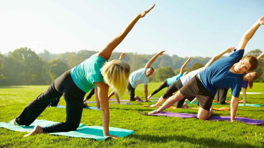Rear of a yoga instructor leading her class during a outdoor lesson